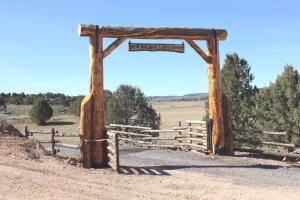 un portail en bois sur un chemin de terre à côté d'une clôture dans l'établissement Sevier River Ranch & Cattle Company, à Hatch