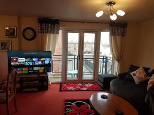 uma sala de estar com uma televisão e uma varanda em Edinburgh City Deluxe Apartment em Edimburgo