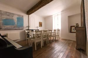 a dining room with a table and chairs and a piano at Les Chambres De Charlotte in Cucuron
