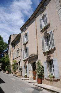 un vieux bâtiment avec volets blancs dans une rue dans l'établissement Les Chambres De Charlotte, à Cucuron