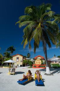 two girls sitting on the beach under a palm tree at Tropical Paradise in Caye Caulker