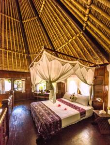 ein Schlafzimmer mit einem Bett in einer Strohhütte in der Unterkunft Seraya Shores Bali in Seraya