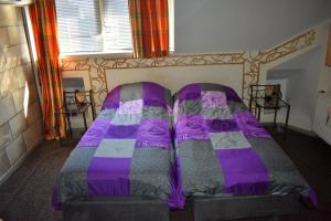 a bed with a purple comforter in a room at Reiderland appartementen centrum Bad Nieuweschans 50 meter supermarkt in Nieuweschans