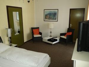 a hotel room with a bed and chairs and a tv at Hotel-Pension Waldeck in Todtmoos