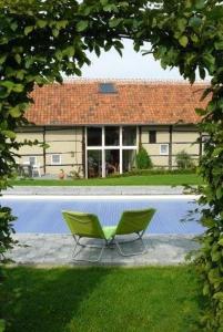 two green chairs sitting in front of a house at Rikkeshoeve vakantiewoning in Sint-Truiden