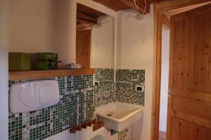 un bagno con lavandino e piastrelle verdi sul muro di Casa Acquarossa a Rubiana