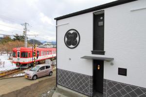 a red train is on the tracks next to a building at Fujinokura Village in Fujikawaguchiko