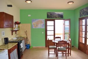 cocina con paredes verdes, mesa y sillas en Apartamento Fritzi, en Ponta do Sol