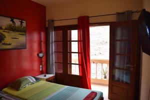 een slaapkamer met rode muren en een bed en een raam bij Apartamento Fritzi in Ponta do Sol