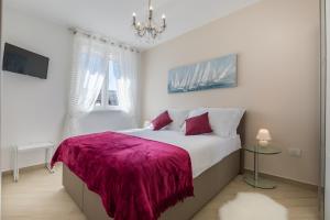 a bedroom with a large bed with a purple blanket at Central Boutique Apartments with balconies, in walking distance to the sea in Zadar