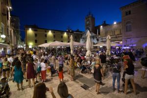 a crowd of people standing in a street at night at Central Boutique Apartments with balconies, in walking distance to the sea in Zadar