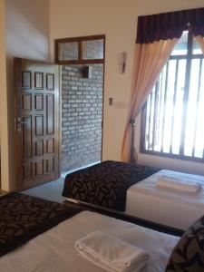 a bedroom with two beds and a large window at So-J Beach Villa in Trincomalee