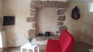 BégardにあるGite La Chouetteの石壁のリビングルーム(赤い椅子付)