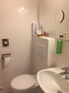 a white bathroom with a toilet and a sink at Hotel Adlerschanze in Schönwald