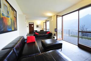 sala de estar con sofá de cuero y balcón en Casa Tulipano Grande, en Faggeto Lario 