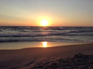 a sunset on a beach with the ocean at u sylwana in Kuźnica