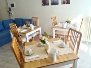 un comedor con mesas y sillas y un sofá azul en B&B Il Giardino In Città - Parcheggio Privato Gratuito en Foggia