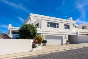 a white house with a white fence in front of it at Apartment Dolphin House in Hermanus