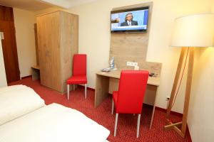 a hotel room with a desk and two red chairs at Hotel Hirsch in Heidenheim