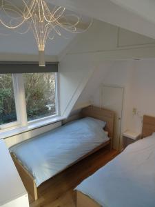 a bedroom with two beds and a window at BeachVibes in Egmond aan Zee