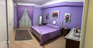 ポルト・エンペードクレにあるAppartamento La Marinaの紫の壁のベッドルーム(ベッド1台付)