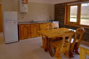 a kitchen with a wooden table and a white refrigerator at Cabañas Posada del Angel in Valle Grande