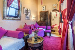 ein lila Zimmer mit Betten, einem Sofa und einem Tisch in der Unterkunft Riad Anabel in Marrakesch