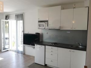 una cucina con armadi bianchi e piano di lavoro nero di Guest House Dragić a Zara (Zadar)