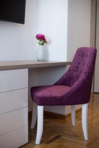 une chaise violette assise à côté d'un bureau avec un vase de fleurs dans l'établissement Dia Belgrade Arena Apartment, à Belgrade