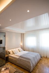 a bedroom with a large bed and a large window at Dia Belgrade Arena Apartment in Belgrade