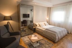 a bedroom with a bed and a chair and a mirror at Dia Belgrade Arena Apartment in Belgrade