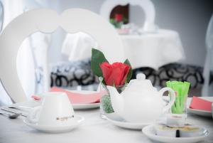 a table with tea cups and a red rose in a vase at Hotel Centrale in Trieste