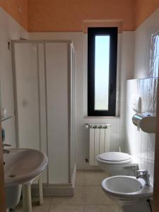 La salle de bains est pourvue de toilettes, d'un lavabo et d'une fenêtre. dans l'établissement Hotel Euro, à San Giovanni Rotondo