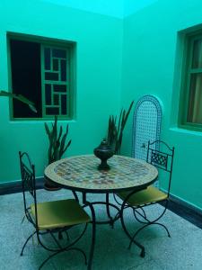 una mesa y sillas en una habitación con una pared verde en Chez Pascal et Nicole, en Oualidia