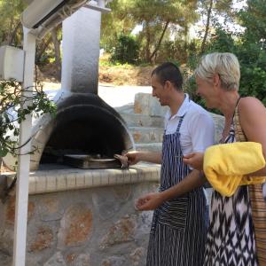 a man and a woman standing in front of an oven at Rosys Little Village in Skala