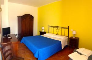 Un dormitorio con una cama y una pared amarilla. en La Terrazza Di San Vito, en San Vito lo Capo