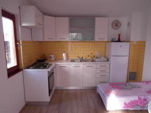 a small kitchen with white cabinets and a white refrigerator at Apartment Antonio in Šibenik +21 photos