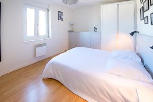 a white bedroom with a white bed and a window at Ocean Apartment in Saint Malo