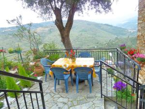 een tafel en stoelen op een balkon met een boom bij Casa Mamma Rosetta in Civezza