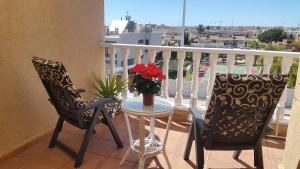 un balcón con 2 sillas y una mesa con flores. en Villa La Zenia, en Playas de Orihuela