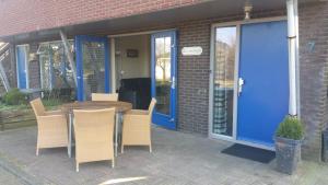 a table and chairs in front of a building with a blue door at de Zanding in Oost-Vlieland