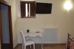 a white desk with a chair and a television on a wall at B&B Il Vicoletto in LʼAquila