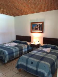 um quarto de hotel com duas camas e uma foto na parede em Hotel Los Mezquites em Tequisquiapan