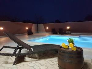 a swimming pool at night with a chair and a table at Villa Komel with Pool in Fažana