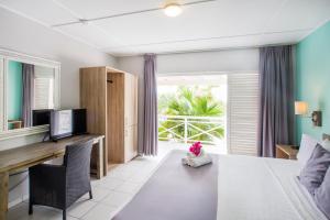 a room with a bed and a desk with a television at Bon Bini Seaside Resort Curacao in Willemstad