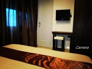 Un dormitorio con una cama, un escritorio y un televisor. en B&B Al Comitato, en Giardini Naxos