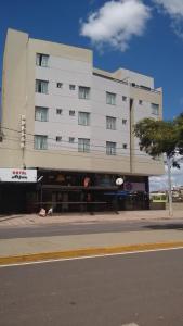 a large white building on the side of a street at Alfon Hotel in Itabira