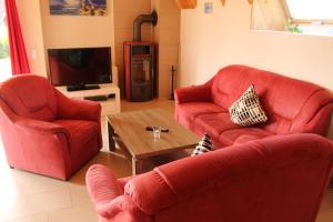 ein Wohnzimmer mit 2 roten Stühlen und einem Tisch in der Unterkunft Ferienhaus Klapötke in Dorum Neufeld