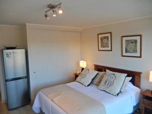 a bedroom with a bed with two pillows and a refrigerator at Dpto4u in Viña del Mar