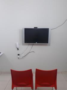 two red chairs and a flat screen tv on a wall at Flats Di Cavalcanti in Uberlândia